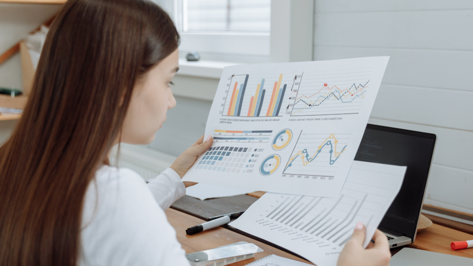 Travel agency professional reviewing financial reports and charts to identify cost reduction strategies.