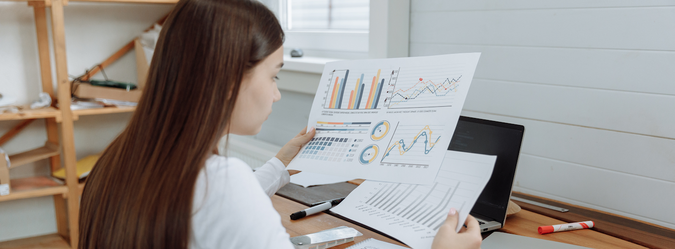 Travel agency professional reviewing financial reports and charts to identify cost reduction strategies.