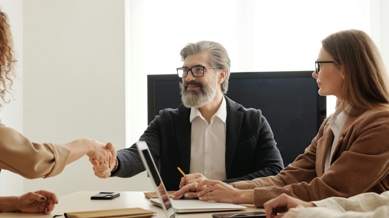 Business partners shaking hands in meeting to finalize reseller partnership for travel agency solutions.