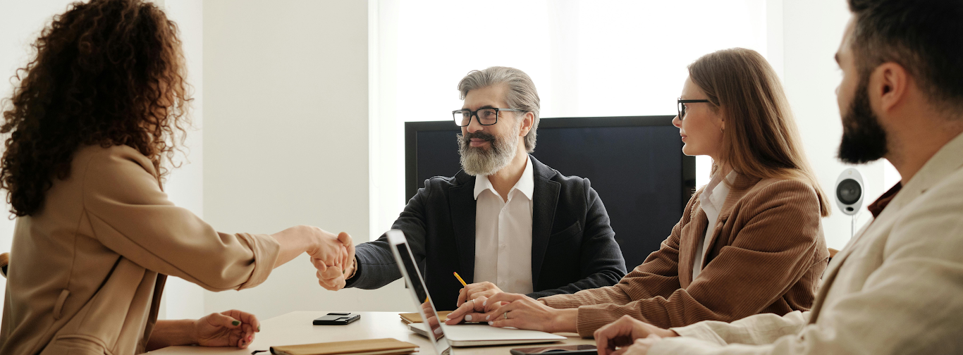 Business partners shaking hands in meeting to finalize reseller partnership for travel agency solutions.