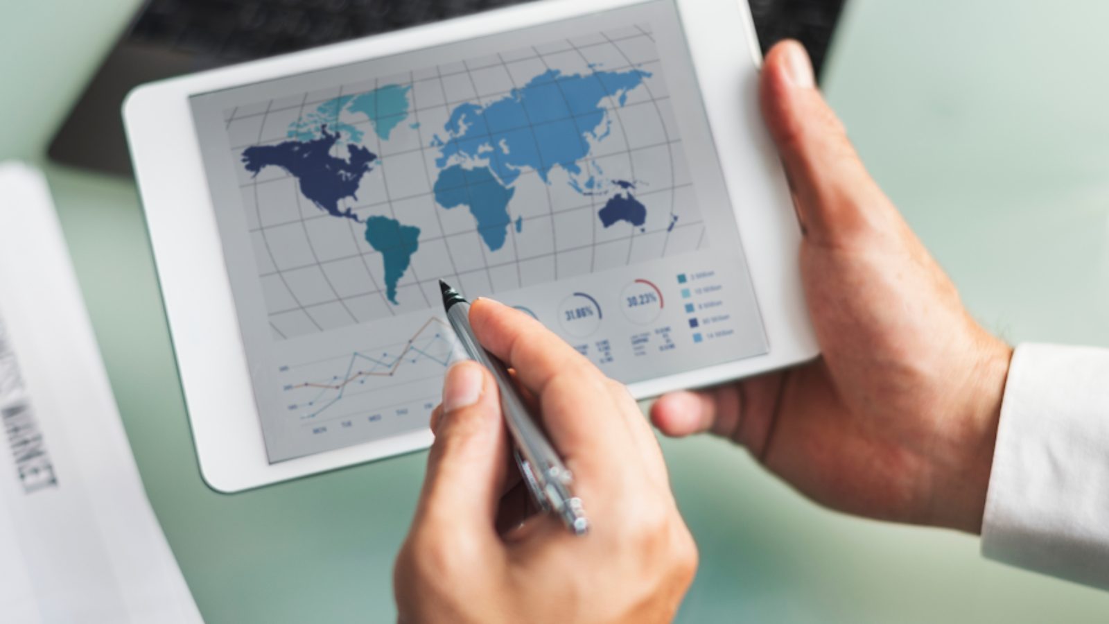 Business professional analyzing global ERP data on tablet with charts and market insights.