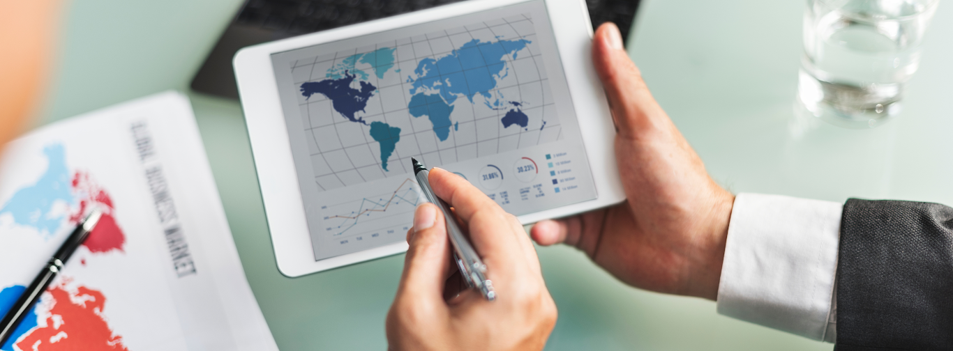 Business professional analyzing global ERP data on tablet with charts and market insights.